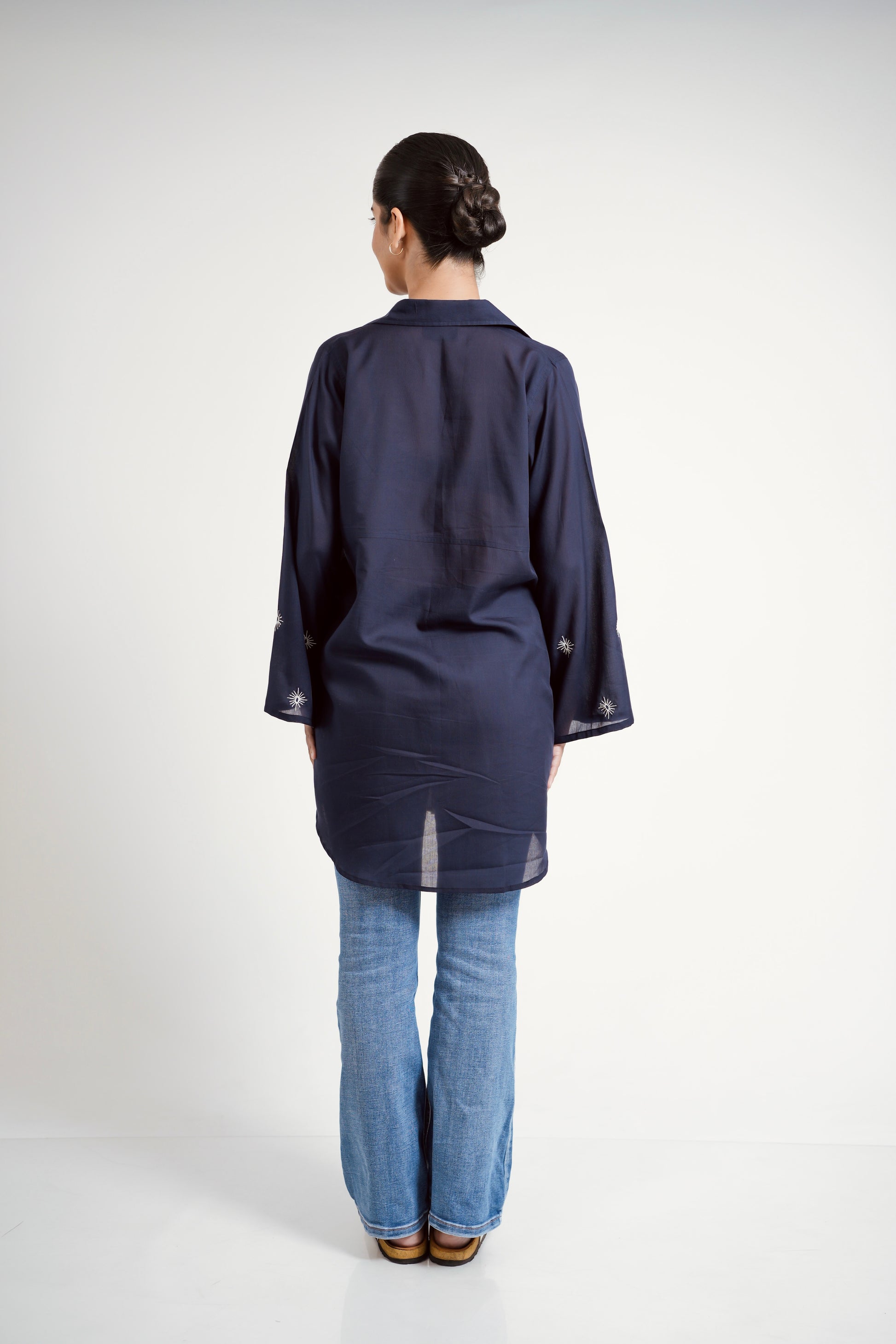 Person wearing a navy blue kimono-style garment on a white background